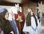 Vier Sternsinger singen. Sie haben eine Spendendose und einen Stern dabei.
